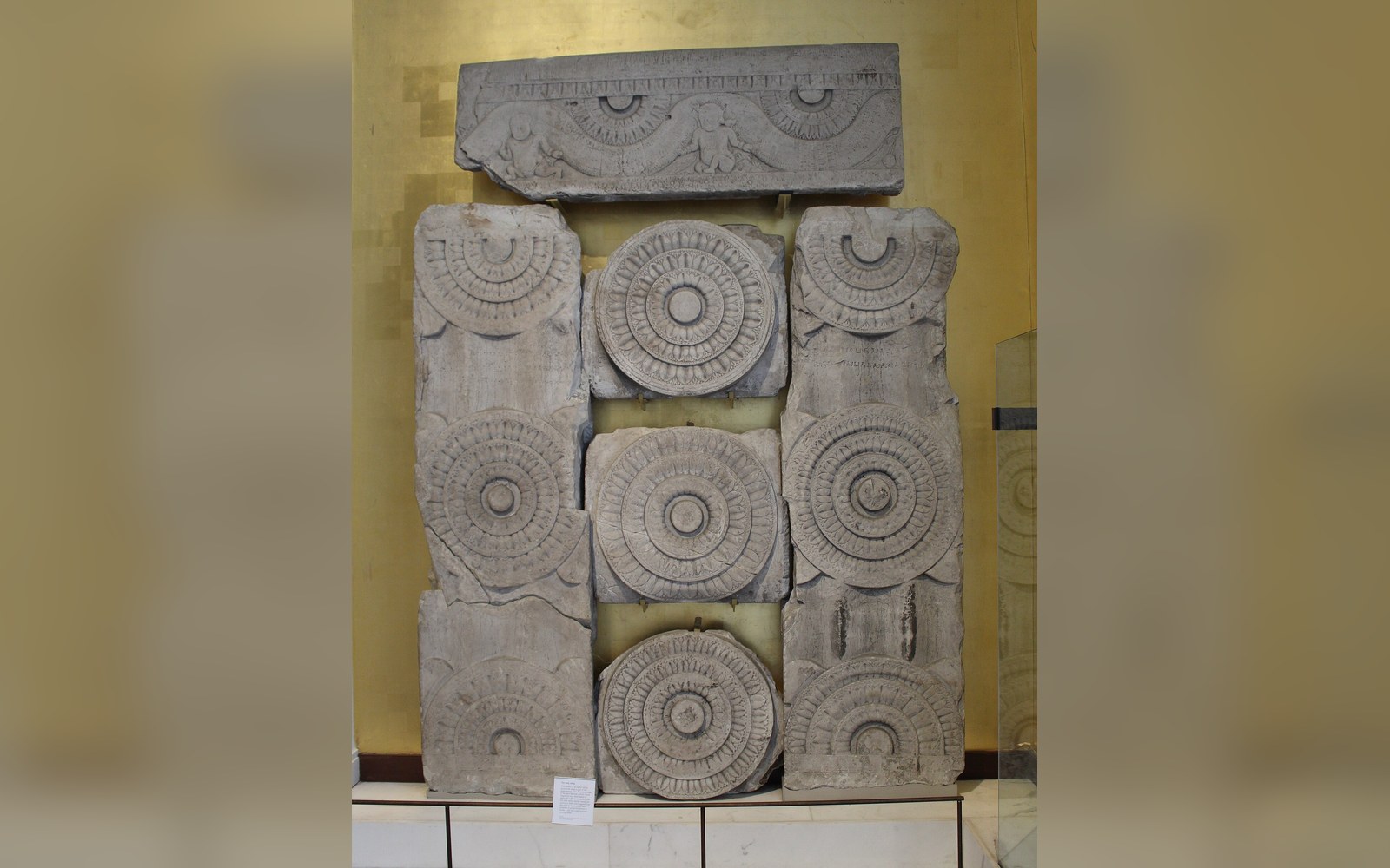 Carved stone panels with circular rosette and swastika motifs displayed in a museum